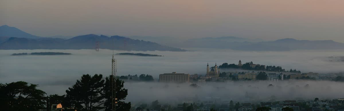 Fog rolling over Twin Peaks at dawn, San Francisco below
