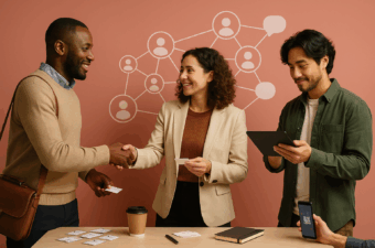 Três profissionais fazem networking em mesa com cartões de visita.