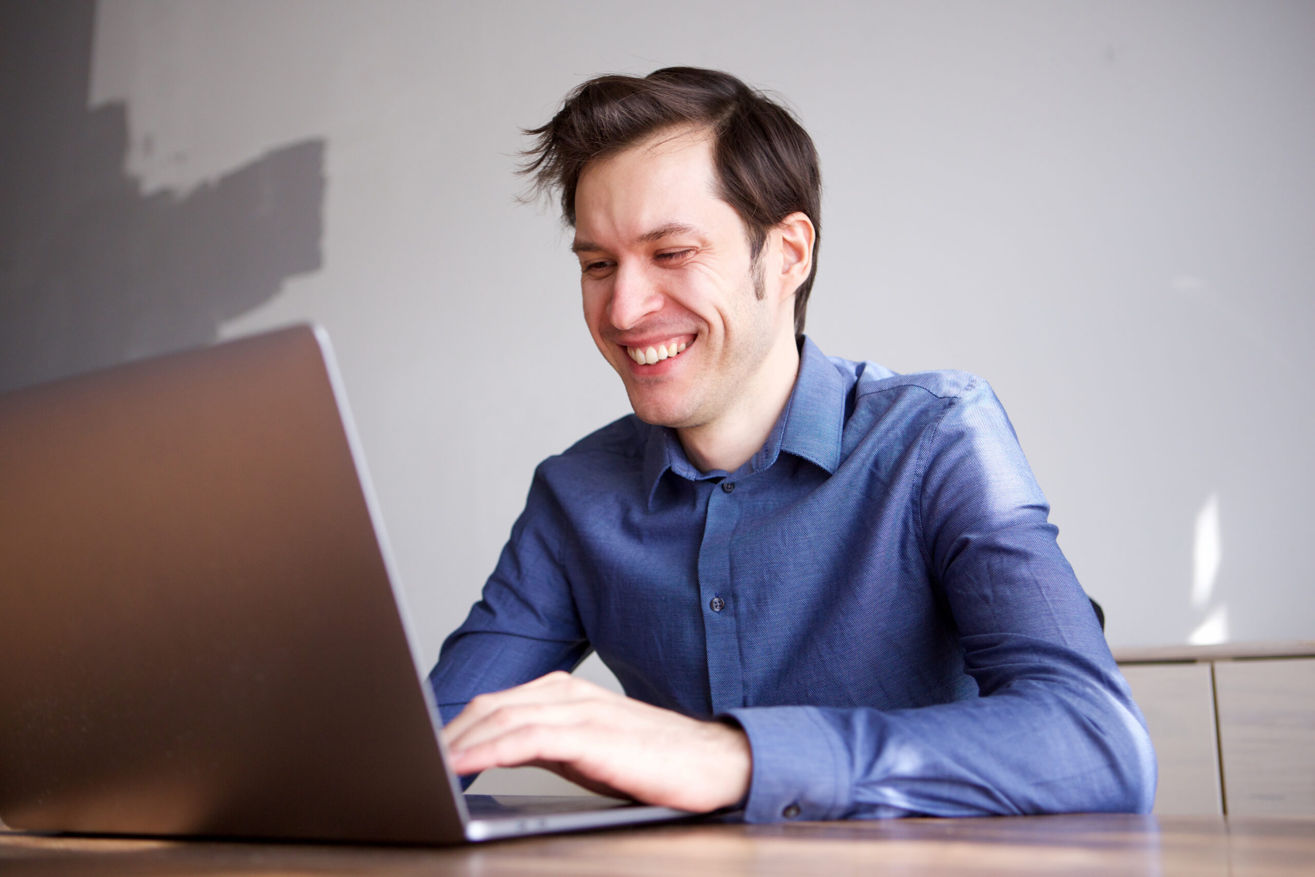 Retrato de perto de homem de negócios sorridente trabalhando em casa no laptop