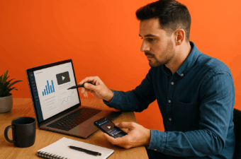 Homem analisando dados em laptop enquanto usa smartphone