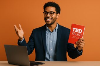 Homem sorridente apresentando livro sobre palestras.