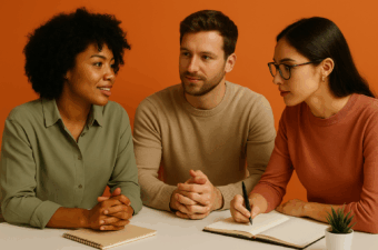 Três profissionais de marketing, de diferentes perfis, reunidos em frente a um fundo laranja, em um ambiente colaborativo, simbolizando o desenvolvimento de soft skills como comunicação e adaptabilidade.