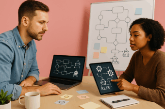 Dois profissionais colaboram sobre automação com IA em estúdio. Notebook e tablet exibem fluxos de automação e ícones de robôs sem texto; ao fundo, whiteboard com diagrama de fluxo. Sobre a mesa, caderno, caneta, post-its, caneca e pequena planta.