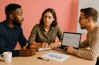 Três profissionais diversos em uma reunião colaborativa em um escritório moderno, analisando gráficos e discutindo estratégias com notebook e quadro branco ao fundo.
