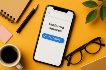 smartphone moderno exibindo “Preferred sources” em uma interface limpa, sobre mesa laranja com xícara de café, caderno, lápis, óculos e planta.