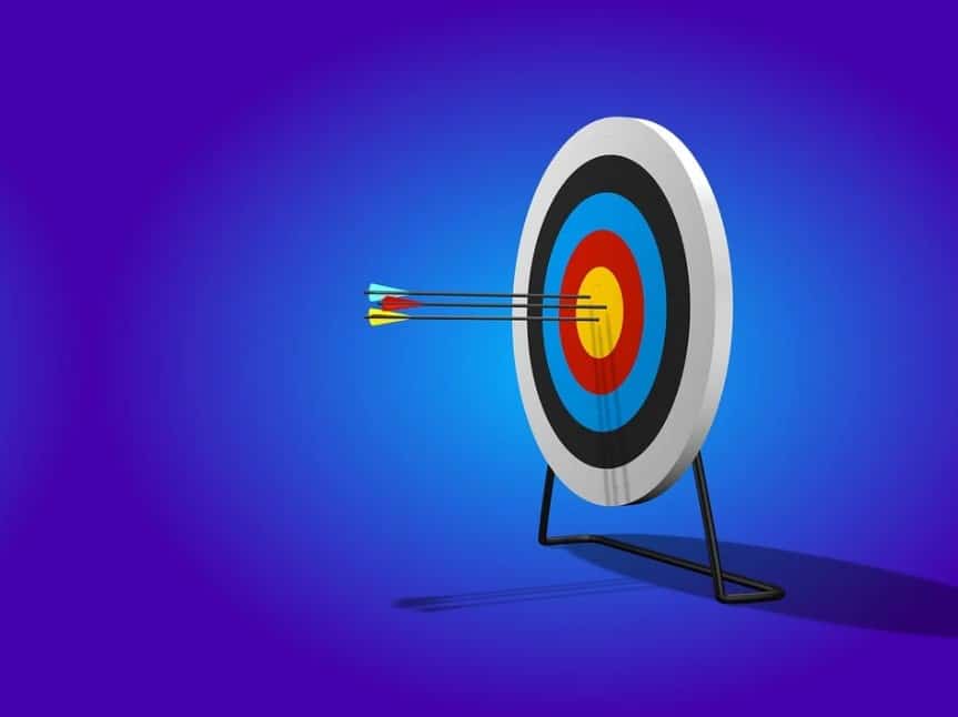 Imagem com fundo azul, com alvo e 3 flechas no meio do alvo. Estabeleça os objetivos e as metas de marketing